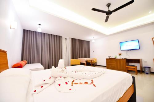 um quarto com uma cama branca e uma ventoinha de tecto em Oasis Riverside Hotel em Kalutara