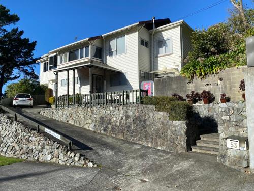 a white house with a stone retaining wall at BBs B&B in Lower Hutt