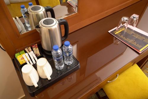 a counter with a drink dispenser and bottles of water at Rose Jeddah Hotel in Jeddah