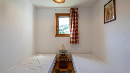 a bedroom with two beds and a window at Les Marmottes- 34- 6 pers in Saint-Sorlin-dʼArves