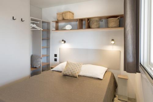 niewielka sypialnia z łóżkiem i oknem w obiekcie Campeggio Ai Colli Fioriti w mieście Castiglione dʼIntelvi