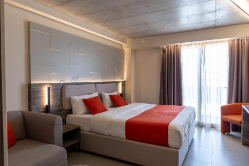 een slaapkamer met een bed, een bank en een stoel bij Alavits Hotel by ST Hotels in Il-Gżira