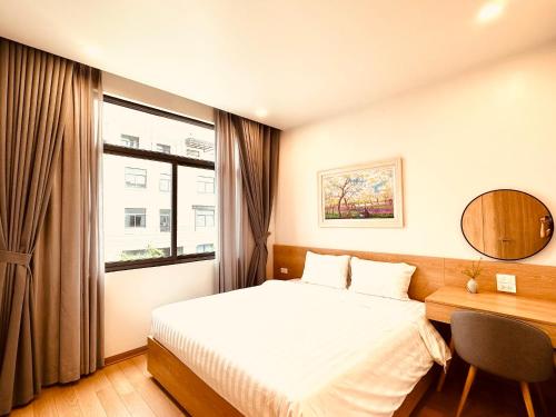 a bedroom with a bed and a desk and a window at Warm & Cozy Apartment in Hai Phong