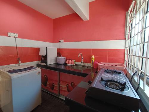 a red kitchen with a stove and a sink at Juwita Homestay Bukit Katil - Free Unifi and 15 Minutes To Town in Melaka