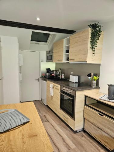 a kitchen with wooden cabinets and a table with a laptop at Gîte de l'Eau Vive in Saint-Martin-dʼUriage