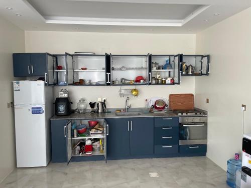 a kitchen with blue cabinets and a white refrigerator at شالية السحاب in Al Ḩazm