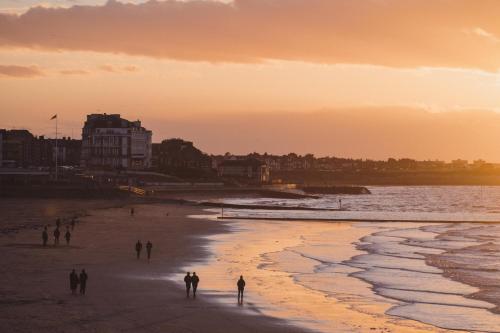 a group of people walking on the beach at sunset at No 42 by GuestHouse, Margate in Margate