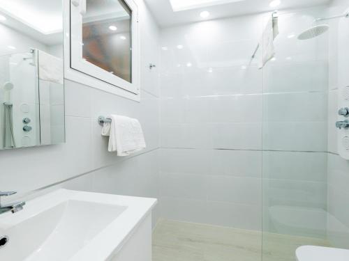 ein weißes Bad mit einer Dusche und einem Waschbecken in der Unterkunft 9 Parque Tropical Apartamento Los Cristianos in Los Cristianos