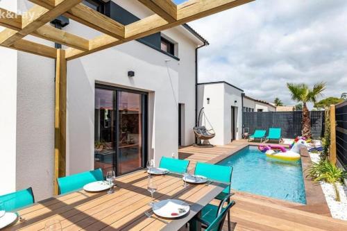 a patio with a table and chairs next to a swimming pool at Villa avec piscine proche plages in Vaux-sur-Mer