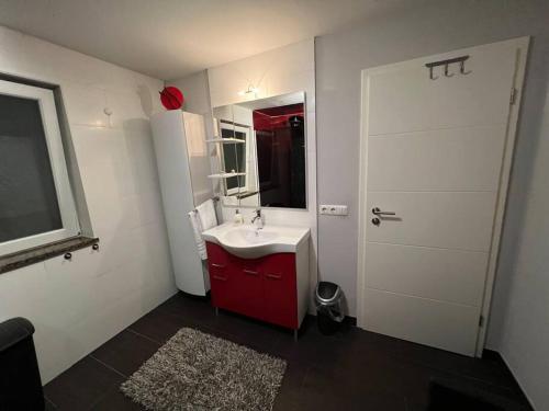 baño con lavabo rojo y puerta blanca en Großzügige Ferienwohnung im Oberland, en Warngau