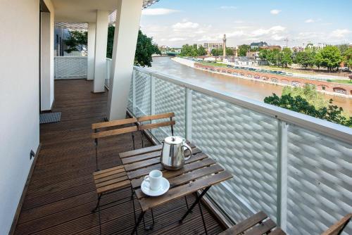 a table and chairs on a balcony with a view of a river at Apartamenty City Tower od WroclawApartament-pl in Wrocław