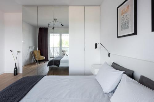 a bedroom with a white bed with a glass wall at Apartamenty City Tower od WroclawApartament-pl in Wrocław