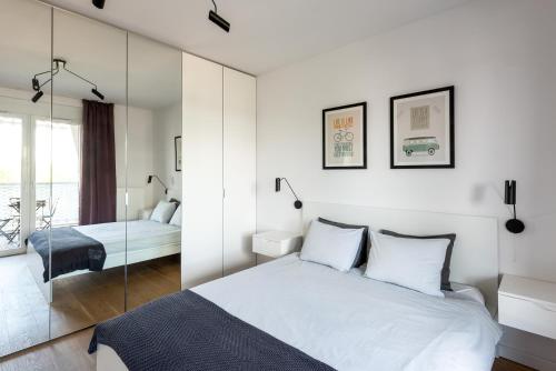 a white bedroom with a bed and a mirror at Apartamenty City Tower od WroclawApartament-pl in Wrocław