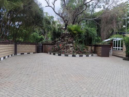 a courtyard with a garden with a tree and a fence at Brooks Lodge in Nakuru
