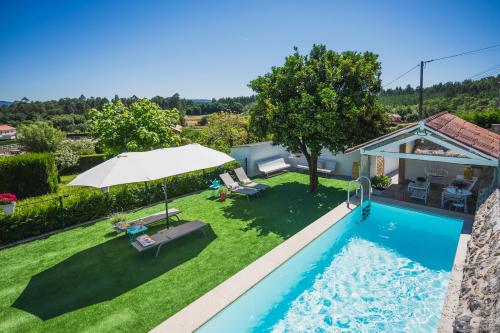 un patio trasero con piscina y sombrilla en La casa de los Barbazanes, en Brión