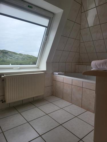 a bathroom with a large window and a tub at Villa am Meer in Westerland (Sylt)