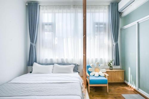 a bedroom with a bed and a blue chair and a window at Dali Ancient City Xinyu Xuan B&B - Erhai Gate Branch in Dali