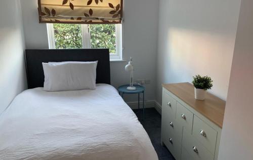 a bedroom with a bed and a dresser and a window at Addlestone - Stylish and modern 2 bedroom apartment in Addlestone