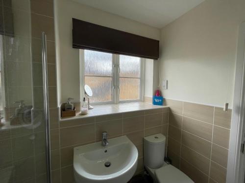 uma casa de banho com um lavatório, um WC e uma janela. em Addlestone - Stylish and modern 2 bedroom apartment em Addlestone