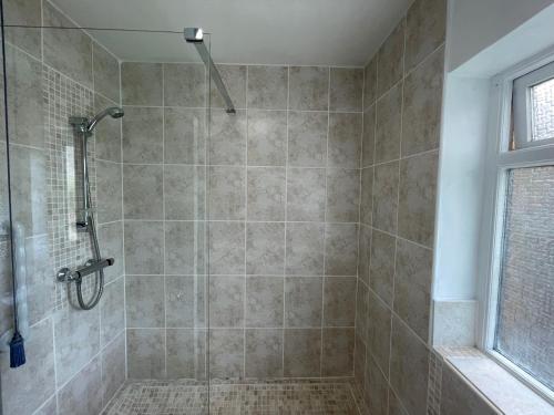 La salle de bains est pourvue d'une douche, de murs carrelés et d'une fenêtre. dans l'établissement Addlestone - Stylish and modern 2 bedroom apartment, à Addlestone