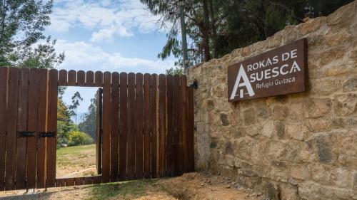 a wooden gate with a sign on a stone wall at Hotel Rokas de Suesca in Suesca