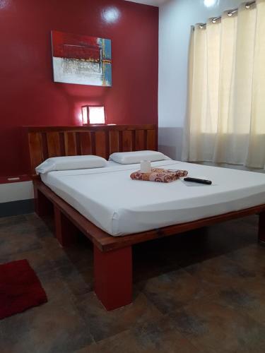 a large bed in a room with a red wall at Marianita's cottages in Mambajao