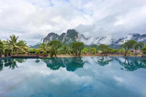 une grande piscine d'eau avec des montagnes en arrière-plan dans l'établissement Soutchai Resort, à Vientiane