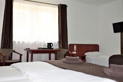 ワルシャワにあるVilla Victoriaのベッド2台、デスク、窓が備わるホテルルームです。