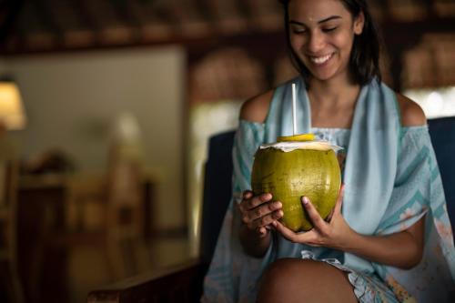 a woman is smiling while holding a coconut at Neeleshwar Hermitage in Nīleshwar