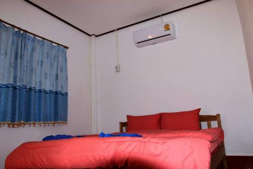 Un dormitorio con una cama con almohadas rojas y una ventana en Soutchai Resort, en Vientiane