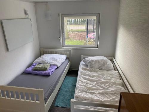 a small room with two beds and a window at Bungalow im Grünen in Werneuchen