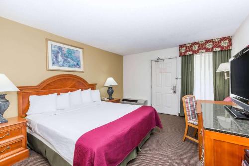 a hotel room with a large bed and a flat screen tv at Days Inn by Wyndham West Des Moines - Clive in Clive