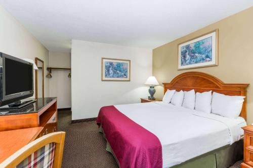 um quarto de hotel com uma cama e uma televisão de ecrã plano em Days Inn by Wyndham West Des Moines - Clive em Clive