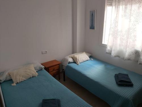 a room with two beds and a window at Ático en Rota, junto a la playa in Rota