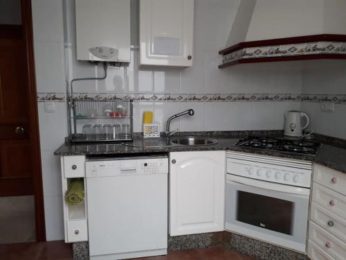 a white kitchen with a sink and a stove at Ático en Rota, junto a la playa in Rota