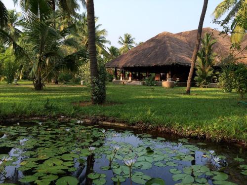 a pond in front of a resort with palm trees at Neeleshwar Hermitage in Nīleshwar