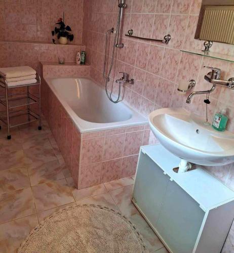 ein rosafarbenes Badezimmer mit einer Badewanne und einem Waschbecken in der Unterkunft Apartmán pod Maliarkou in Východná