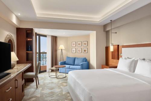 Pokój hotelowy z łóżkiem i niebieskim krzesłem w obiekcie Ramses Hilton Hotel & Casino w Kairze