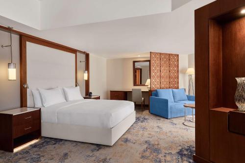 a hotel room with a bed and a blue chair at Ramses Hilton Hotel & Casino in Cairo