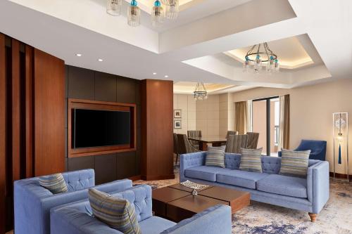 a living room with blue couches and a flat screen tv at Ramses Hilton Hotel & Casino in Cairo