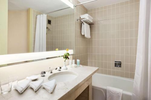 a bathroom with a sink and a mirror and a tub at Ramses Hilton Hotel & Casino in Cairo