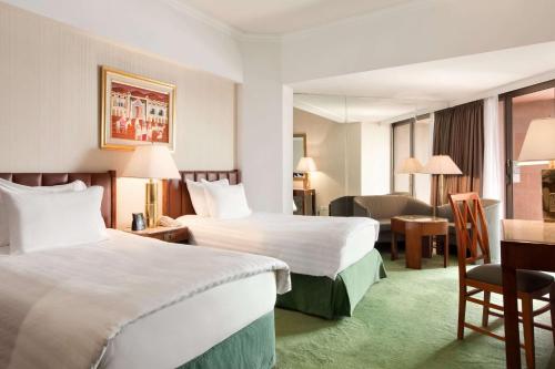 a hotel room with two beds and a desk at Ramses Hilton Hotel & Casino in Cairo
