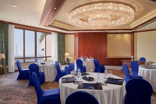 a conference room with tables and blue chairs and a chandelier at Ramses Hilton Hotel & Casino in Cairo