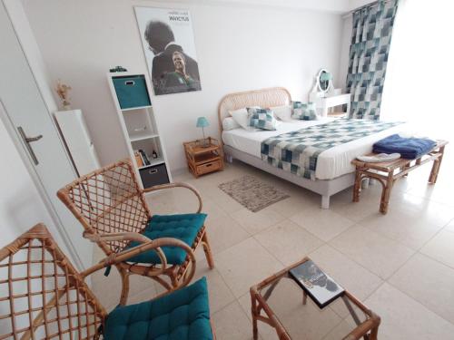ein Schlafzimmer mit einem Bett und Stühlen in einem Zimmer in der Unterkunft TOUTUNCINEMER in Saleilles