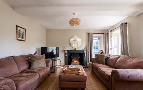 a living room with two brown couches and a fireplace at Holmleigh cottage in Tintern