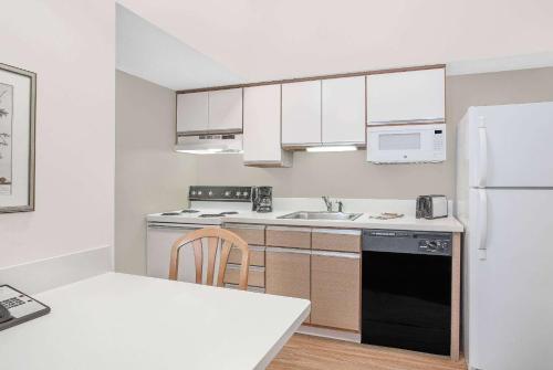 a kitchen with white cabinets and a black refrigerator at Hawthorn Extended Stay by Wyndham Green Bay in Green Bay