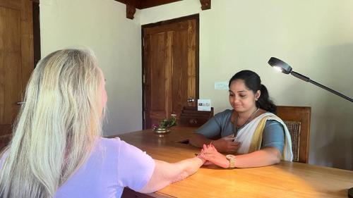 two women sitting at a table talking to a woman at Neeleshwar Hermitage in Nīleshwar