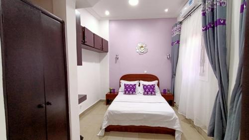 a bedroom with a bed with purple pillows at Kharism'Apparts in Mvan