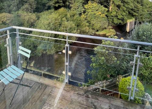 una terraza de madera con un banco y árboles en Modern Apartment by river - 20 mins to Belfast, en Dunadry