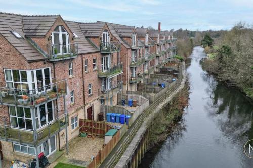 a row of brick buildings next to a river at Modern Apartment by river - 20 mins to Belfast in Dunadry